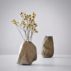 Two stone vases with dried yellow flowers on a light gray background