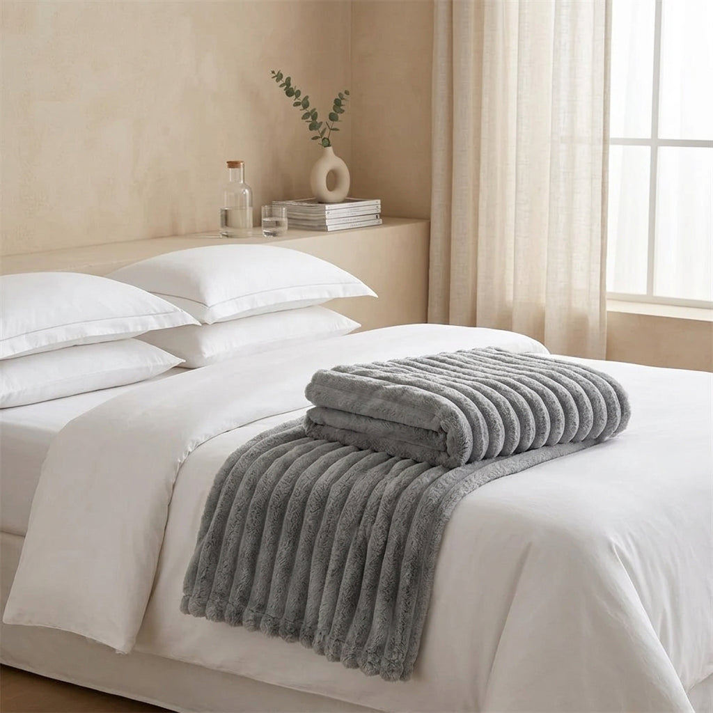 Person holding a large gray textured blanket in a room with a couch and coffee table.