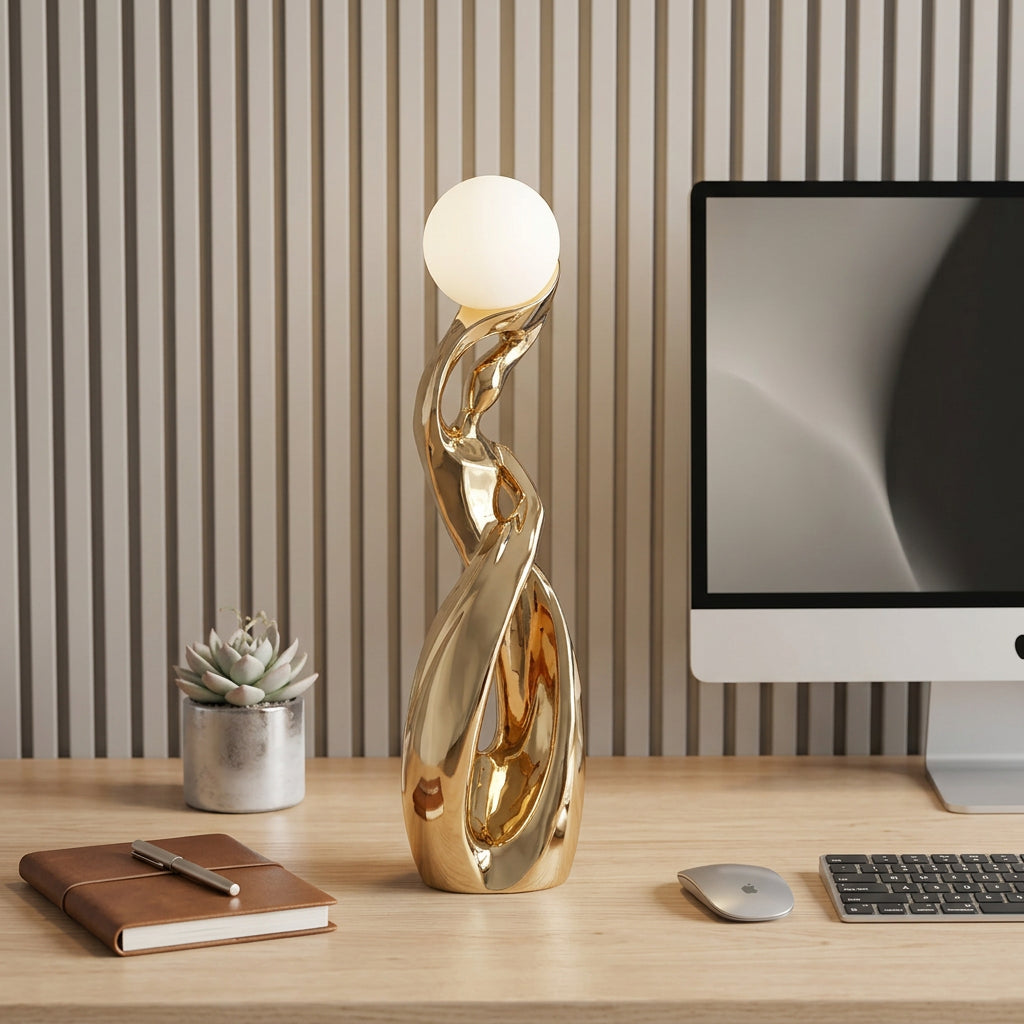 Gold floor lamp on a desk with books and a computer monitor in the background
