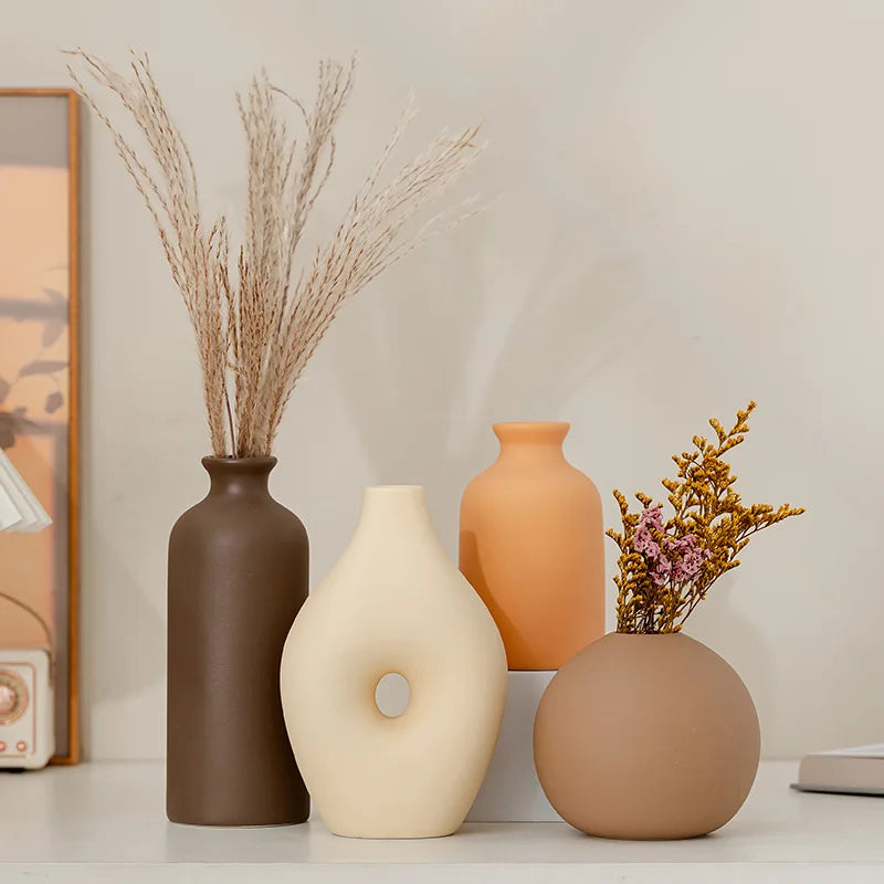 Four decorative vases with dried plants on a neutral background
