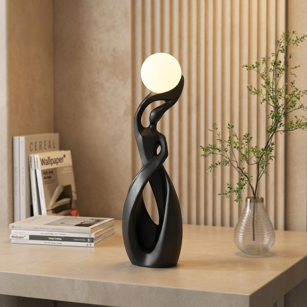 Decorative black lamp with a round light bulb on a table next to a plant and magazine.
