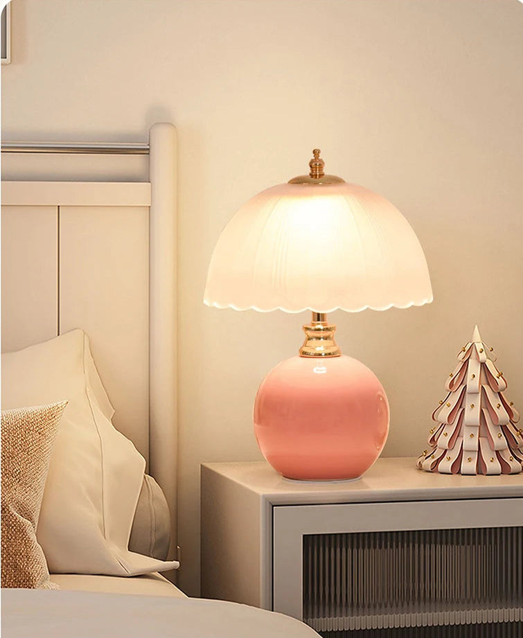Pink table lamp on a nightstand next to a bed with a decorative item.